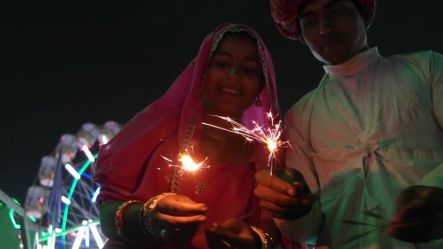 Indian couple in traditional dress with fire sparkle cracker at Diwali Mela festival in India 