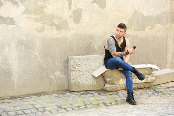 Fototapeta na wymiar Young tattooed man posing on dirty concrete wall background