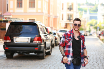 Young tattooed man posing on blurred city street background