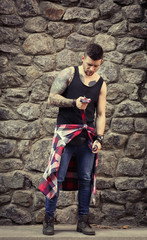 Young tattooed man posing on stone wall background
