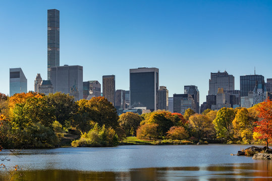 Fall in Central Park at The Lake with Midtown skyscrapers. Sunrise view with colorful Autumn foliage. Manhattan, New York City
