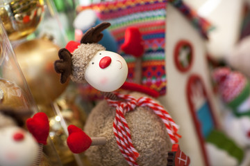 soft toy Christmas deer with a scarf on the background of the house