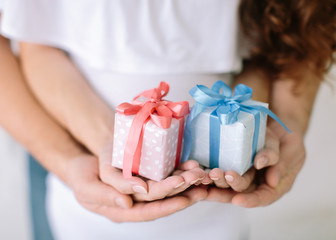 the young family holds a pink and blue gift surprise in hand.