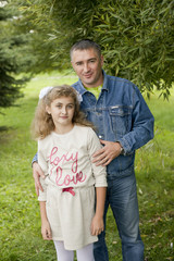 Fototapeta premium Father hugs daughter teen summer outdoors, happy family resting