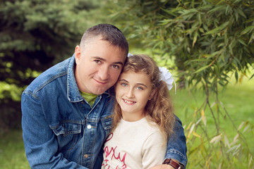 Father hugs daughter teen summer outdoors, happy family resting