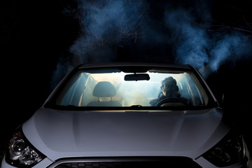 girl smoking cigarette in car full of smoke at night with gas mask