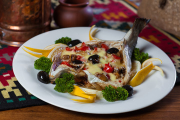 stuffed fish with olives and herbs on a white plate