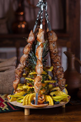 Grilled meat on a skewer with fruits and pineapple on the table