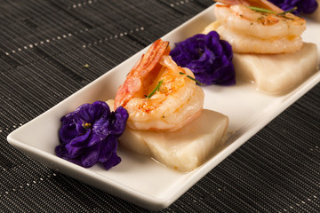 Grilled shrimp with raw nail fish on white plate at table