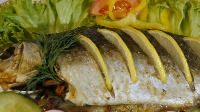 Baked carp with spices and lemon on white pan top view
