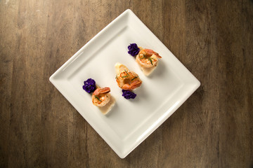 Grilled shrimp with raw nail fish on white plate at table