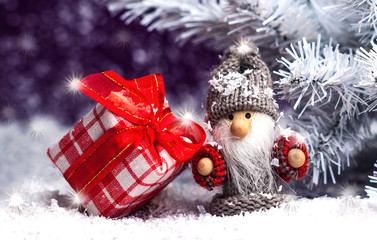 little gnome with a red gift near spruce