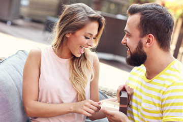 Young man proposing to beautiful woman outdoors