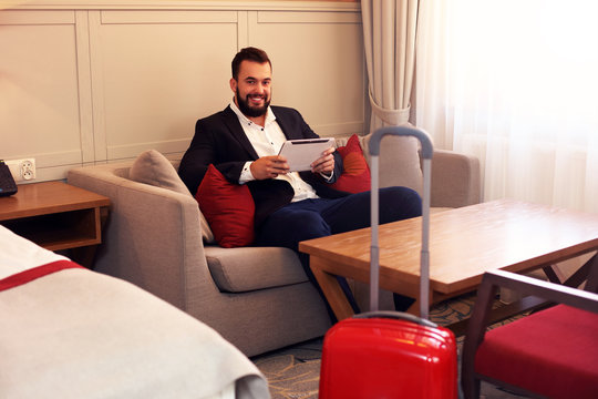 Young businessman sitting in hotel room with tablet