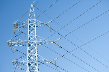 High voltage metal power pole with wires tangle on blue sky background