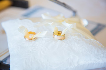 Fototapeta na wymiar Wedding gold rings lie on white pillow, closeup