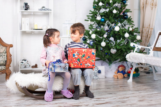 Due bambini che si guardano con i regali di natale nelle mani