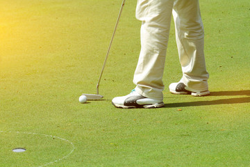 Obraz na płótnie Canvas Male golfer putting a golf ball in to hole