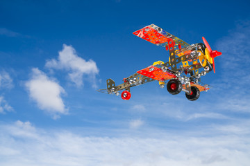 Toy plane built with small pieces of metal and plastic, shot on sky background