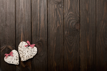 Concept of Valentine's Day. Wicker hearts on dark wooden backgro