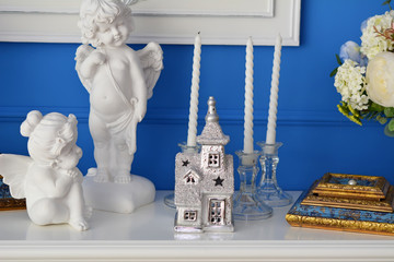Белые скульптуры, свечи, сувениры на полке