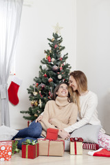 Obraz na płótnie Canvas Young beautiful women next to Christmas tree with Christmas presents, Christmas morning
