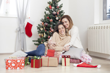 Obraz na płótnie Canvas Young beautiful women next to Christmas tree with Christmas presents, Christmas morning