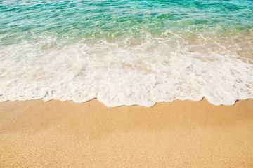 Background wave of Turquoise Sea with foam on sandy beach.