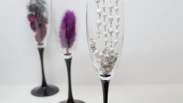 Stylish colored beads dropped into a glass of champagne. Fashionable Attributes for interior decoration. 3 glasses on a high leg close-up. Light room.