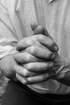 A man holds his hands in front of him. Fingers intertwined.
