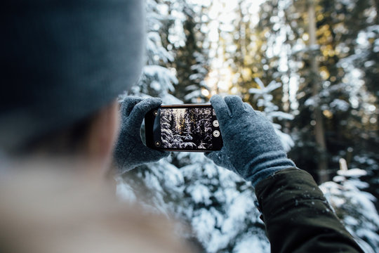 Girl takes a picture of snow-covered trees in the winter forest.