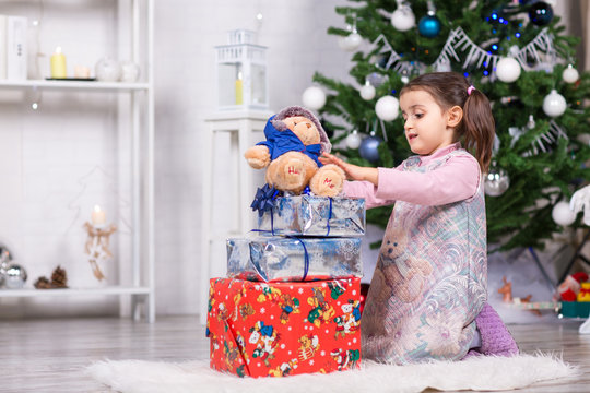 Bambina che gioca con un peluche e regali di Natale