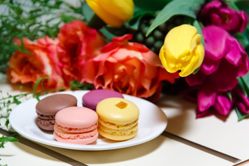 Macaroons on plate with bunch of flowers