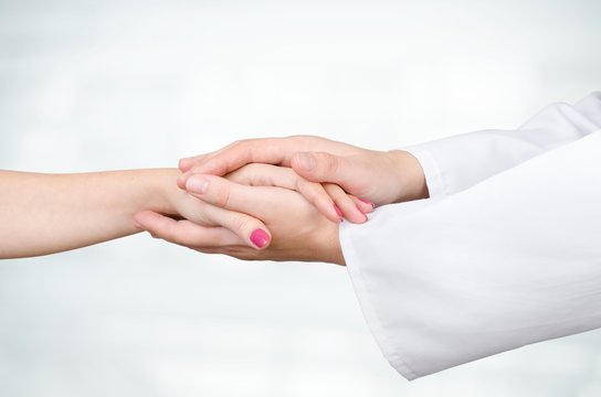 Doctor holding patient hand close up