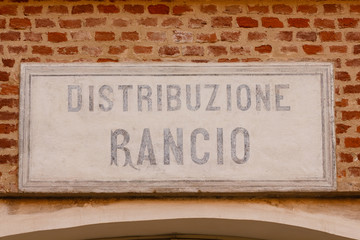   old sign ration-distribution written in  italian language / sign made of cement indicating the writing ration-distribution  on a bricks wall