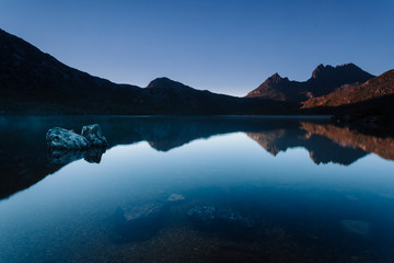 Early morning light illuminates mountain peaks reflecting in the