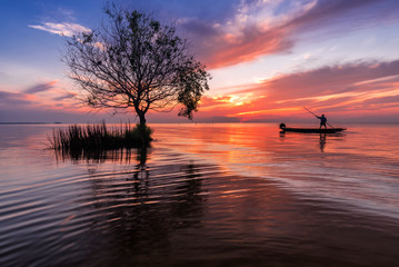 Fishermen on a boat in the lake at sunrise beautiful sky