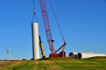 Installing base section of tower for wind turbine as part of wind farm generating clean power in ND.