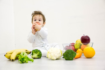 Fototapeta premium baby surrounded with fruits and vegetables, healthy child nutrition