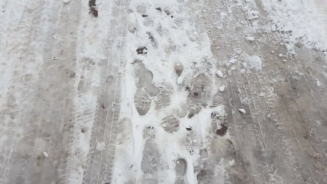 Treads and footprints in snow, city street covered in snow. Steadicam shot.