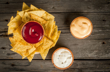 Snack for party, chips, nachos with sauces: tomato (ketchup), cheese and mayonnaise (tartar), top view, copy space 