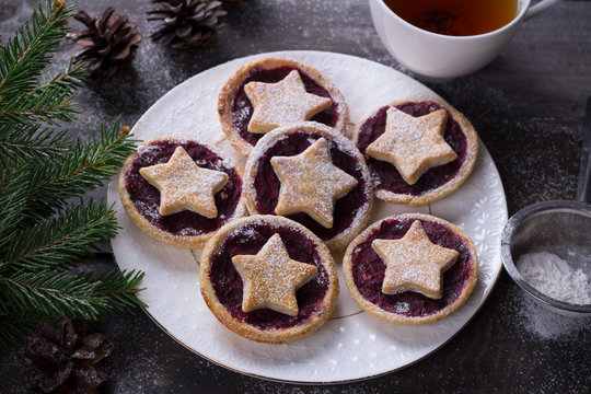 Christmas holiday cookies with cranberry jam, sprinkled with powdered sugar on a wooden table with traditional decorations