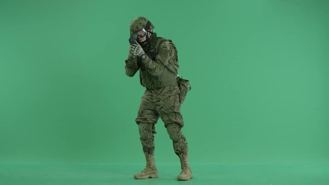 Soldier standing and targeting at camera at green screen