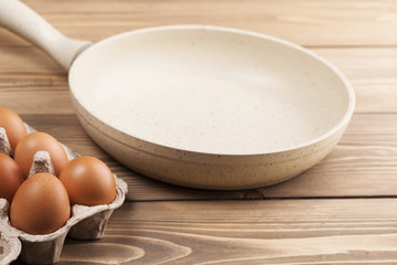 Cooking concept, frying pan and eggs on wooden background