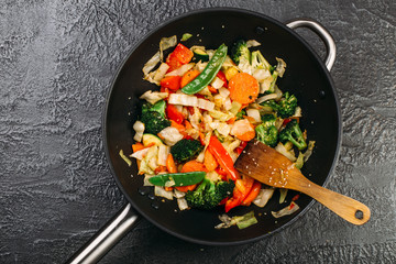Tasty vegetable dish with broccoli and colorful peppers cooked in oil stained asian wok recipe  - obrazy, fototapety, plakaty