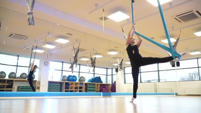 Girl doing the splits while standing with one foot in a hammock to fly yoga