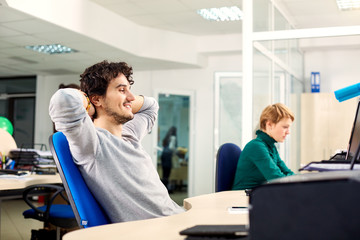 Successful businessman sitting pretty at the table in office, dreaming, resting on job