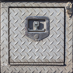 Close-up of old outdoor steel utility cover with diamond plating