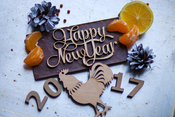 Wooden inscription Happy New Year and a rooster is on top of the