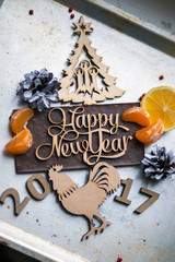 Wooden inscription Happy New Year and a rooster is on top of the